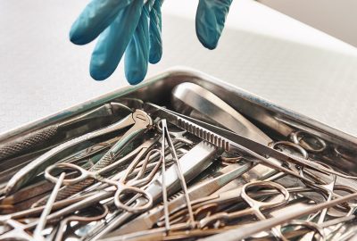 I need this tool. Vet's hands in protective gloves taking the necessary medical instrument that